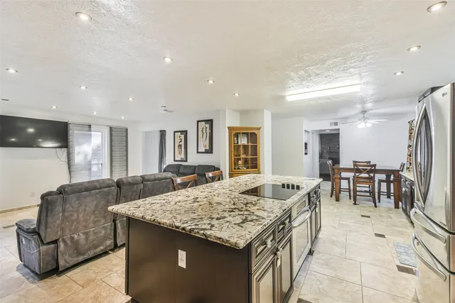 a kitchen with granite countertop kitchen island a sink and a refrigerator
