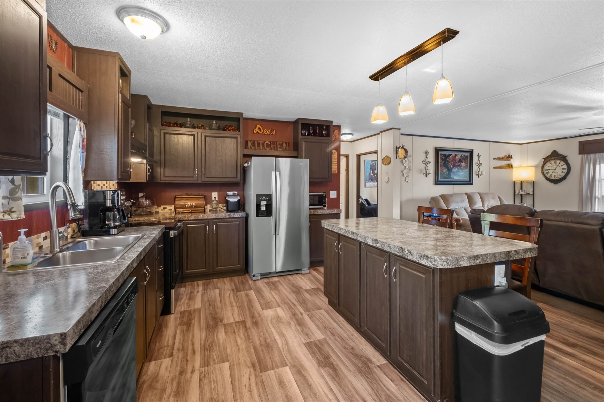 57443 667th Colcord, OK 74338 - Photo 16 of 51 Kitchen featuring wood-finish flooring, dark wood cabinetry, a center island with countertop, and a stainless steel refrigerator
