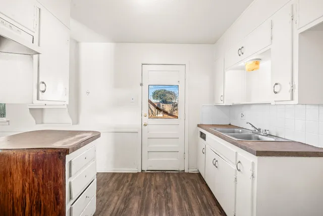 a kitchen with white cabinets and wooden floor