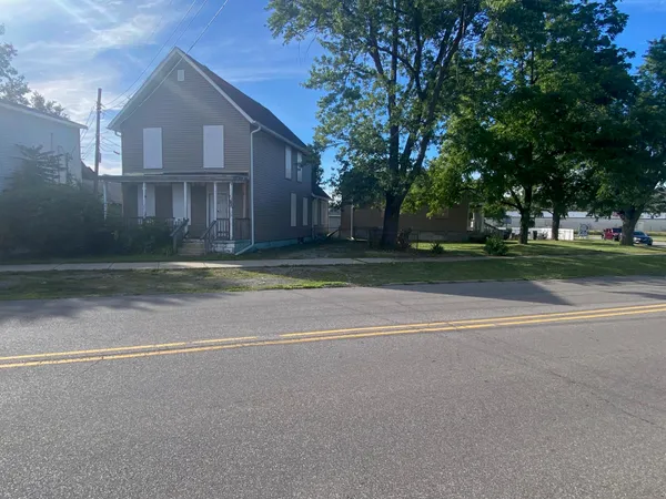 a view of a house with a yard and large trees