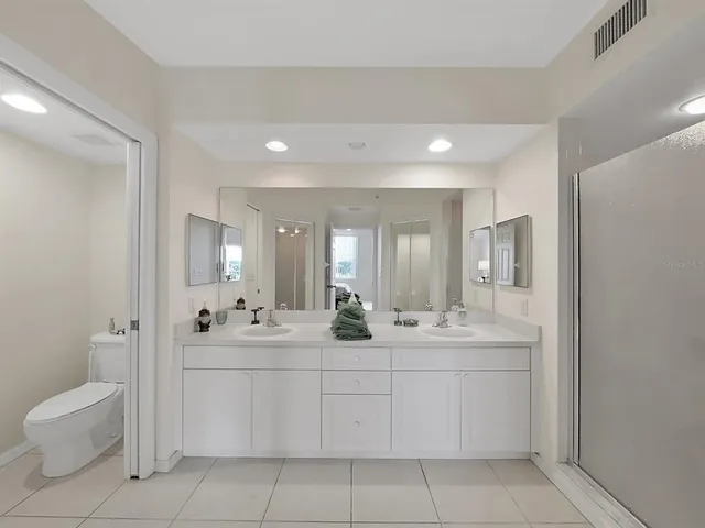 a bathroom with a double vanity sink toilet and a mirror