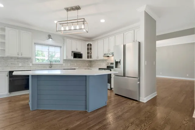 a kitchen with a sink white cabinets and stainless steel appliances