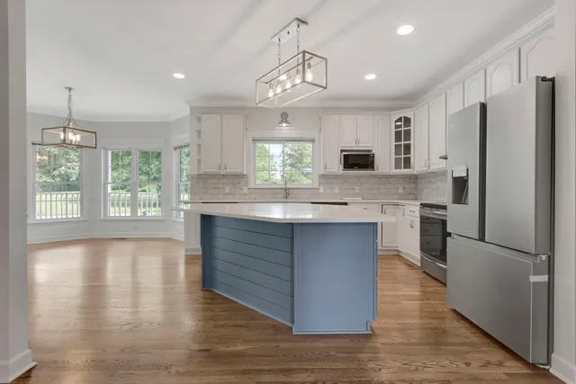 a kitchen with kitchen island a sink wooden floor and stainless steel appliances