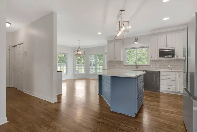 a kitchen with stainless steel appliances granite countertop a white cabinets a sink a stove a refrigerator and white cabinets