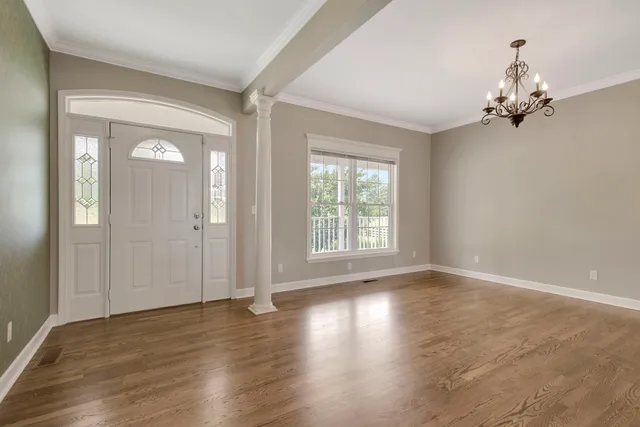 a view of an empty room with wooden floor fireplace and a window