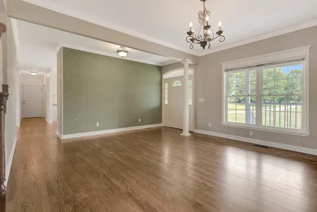 an empty room with wooden floor fireplace and windows