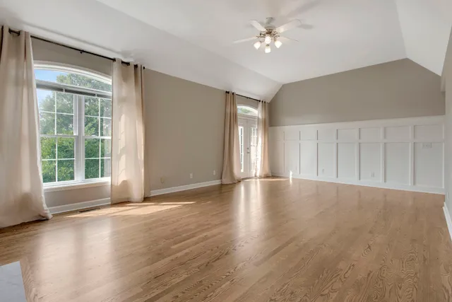 a view of a livingroom with wooden floor a ceiling fan a fireplace and entryway