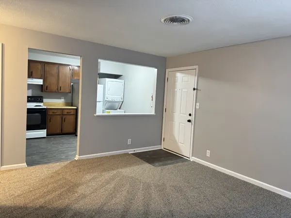 an empty room with kitchen and windows
