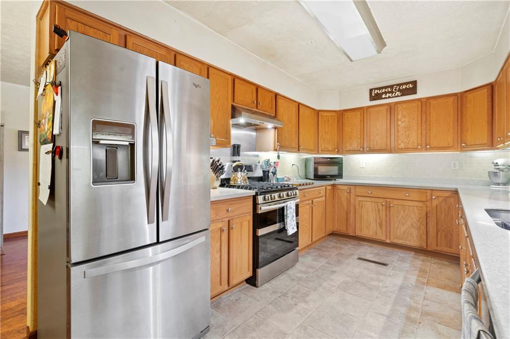 354 Storey Frye Road Ruffs Dale, PA 15679 - Photo 7 of 22 a kitchen with granite countertop a refrigerator a sink a stove and cabinets