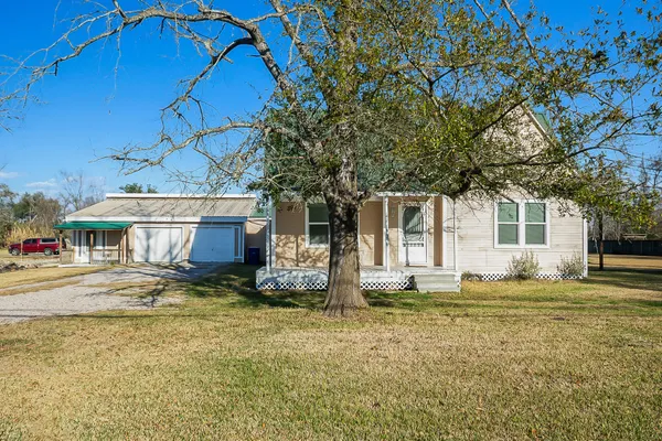 a view of a house with a big yard and large tree