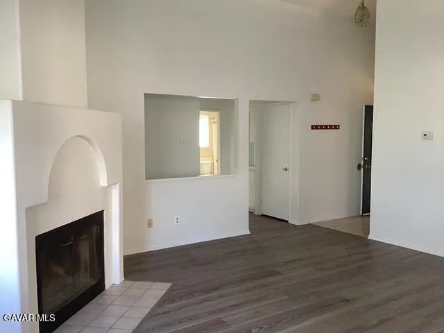 an empty room with wooden floor fireplace and windows