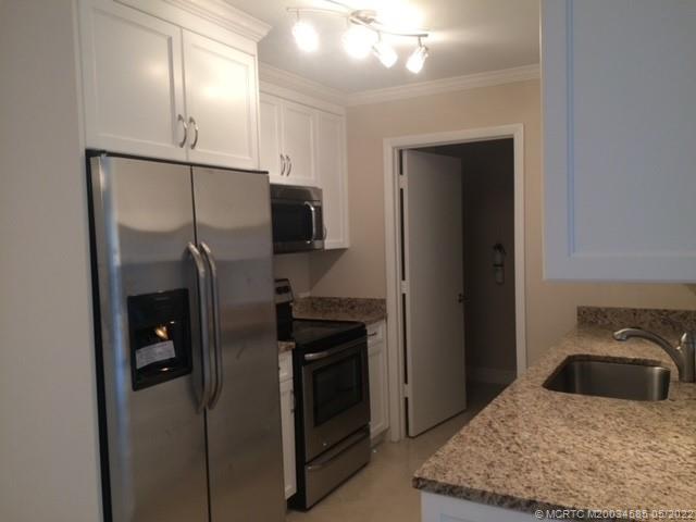 3994 Northwest Cinnamon Tree Circle Jensen Beach, FL 34957 - Photo 13 of 14 a kitchen with a refrigerator and a sink