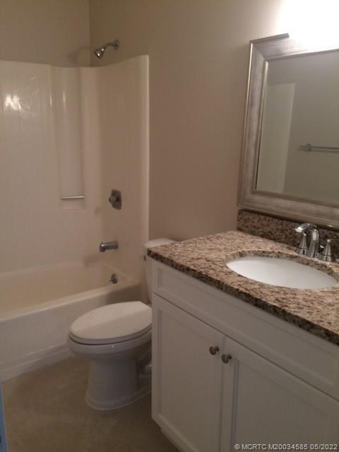 3994 Northwest Cinnamon Tree Circle Jensen Beach, FL 34957 - Photo 14 of 14 a bathroom with a granite countertop sink toilet and shower