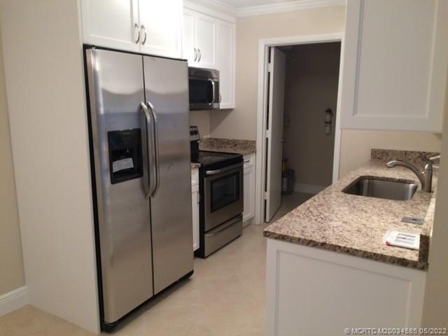 3994 Northwest Cinnamon Tree Circle Jensen Beach, FL 34957 - Photo 3 of 14 a kitchen with metallic refrigerator and microwave