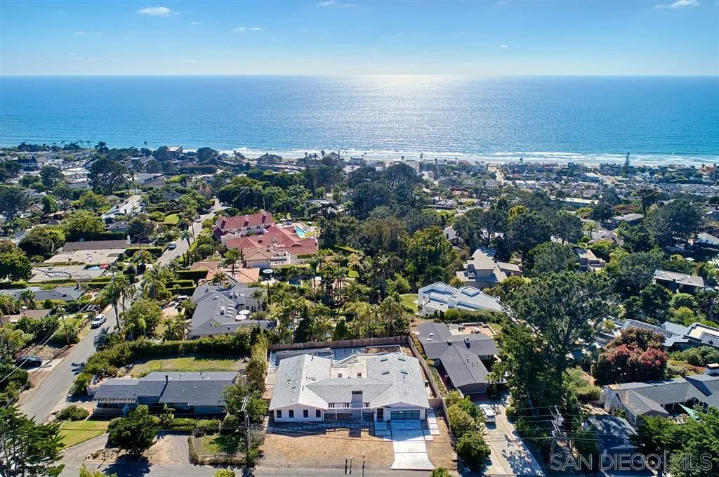 an aerial view of a city with lots of residential buildings and ocean view in back
