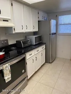 a kitchen with granite countertop white cabinets and black appliances