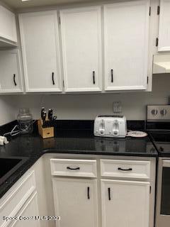 1830 North Atlantic Avenue, Unit 205 Cocoa Beach, FL 32931 - Photo 9 of 28 a kitchen with granite countertop white cabinets and black appliances