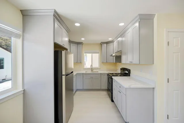 a kitchen with a sink a refrigerator a stove and cabinets