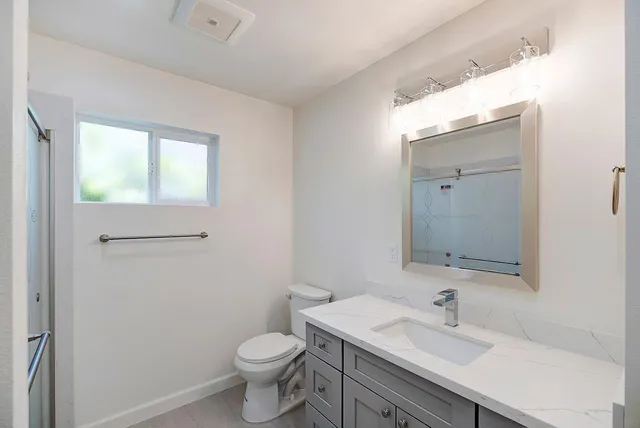 a bathroom with a sink a toilet and a mirror