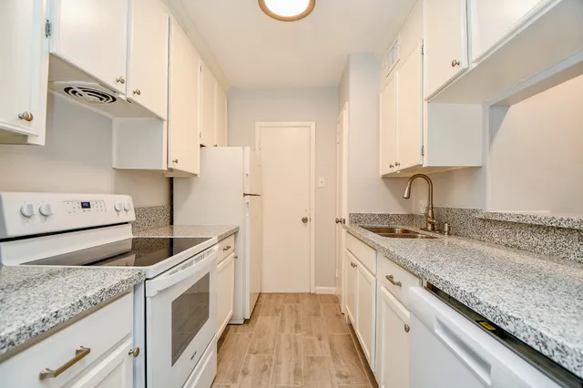 a kitchen with granite countertop a sink stove and cabinets