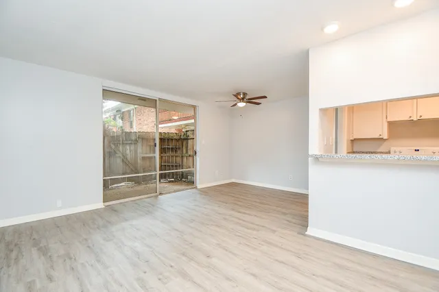 an empty room with wooden floor closet and windows