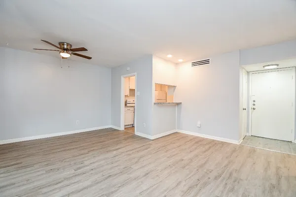 an empty room with wooden floor closet and windows