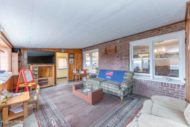 a living room with furniture a flat screen tv and a floor to ceiling window