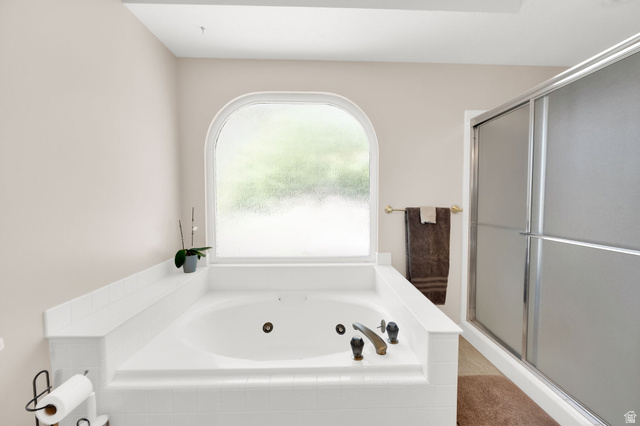 5057 South Ridgedale Drive Ogden, UT 84403 - Photo 20 of 69 Soaking tub with tiled surround and an arched privacy window, complemented by a separate enclosed shower with frosted glass doors