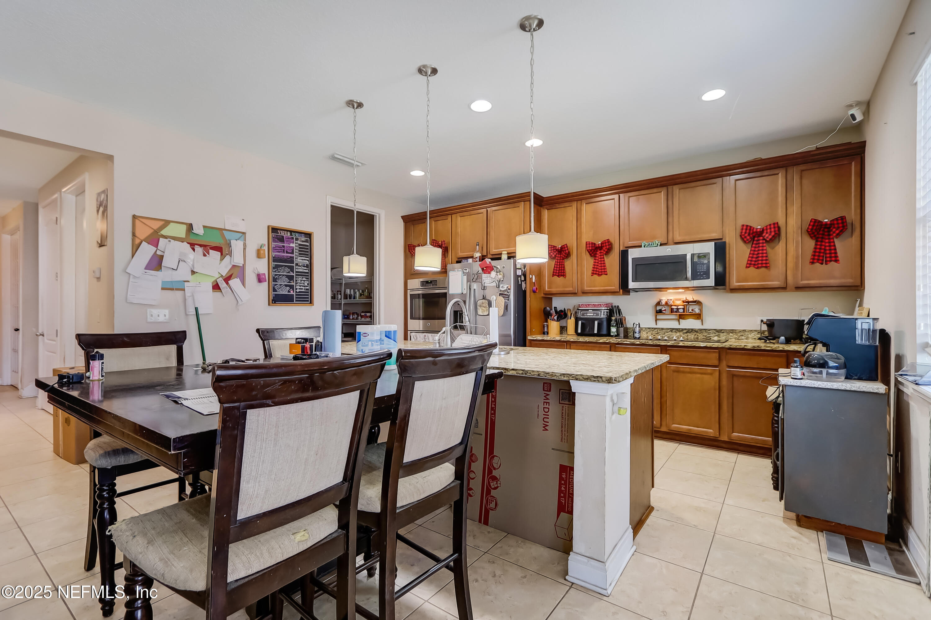 1071 Wetland Ridge Circle Middleburg, FL 32068 - Photo 13 of 41 a kitchen with stainless steel appliances kitchen island granite countertop a table chairs sink and cabinets