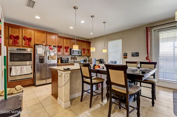 a kitchen with stainless steel appliances kitchen island granite countertop a dining table chairs refrigerator and sink