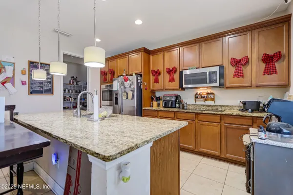 a kitchen with stainless steel appliances granite countertop a sink dishwasher and refrigerator with wooden cabinets