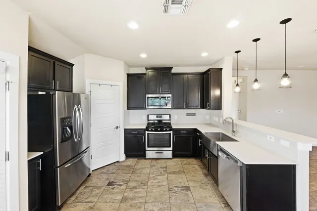 a large kitchen with a stove a sink dishwasher a refrigerator and a oven with wooden floor