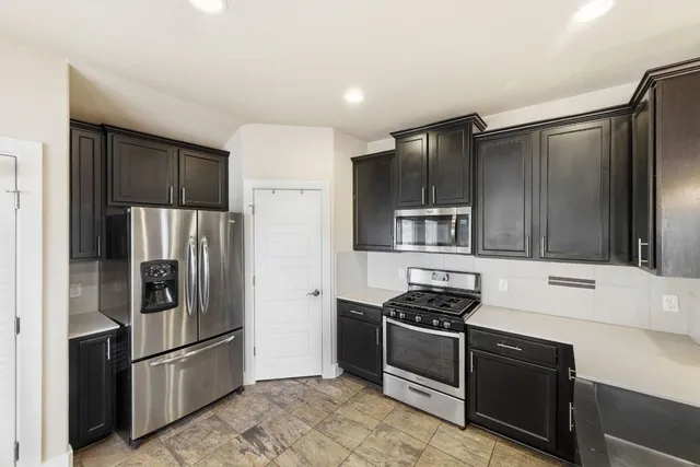 a large kitchen with stainless steel appliances kitchen island granite countertop a refrigerator and a sink