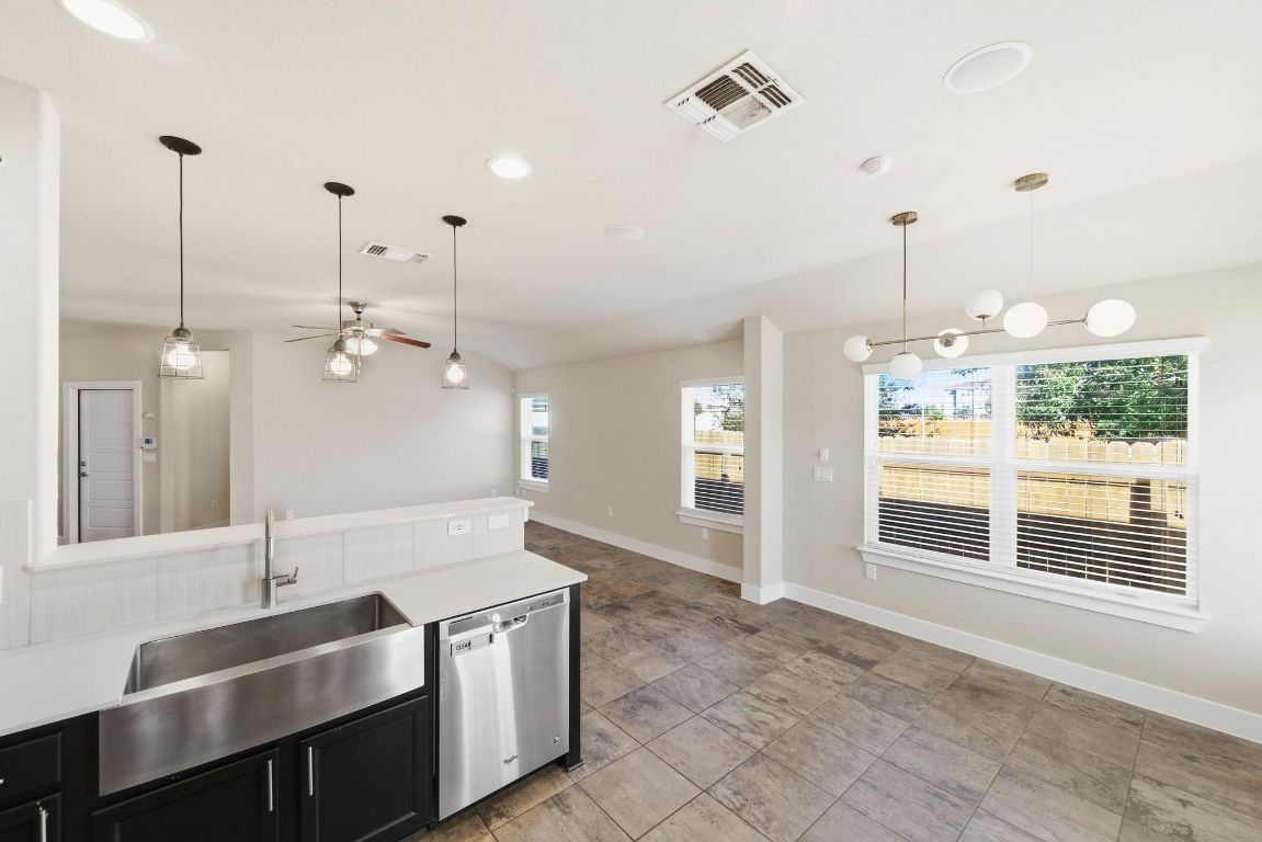 7013 Brick Slope Path Austin, TX 78744 - Photo 12 of 28 Kitchen with decorative light fixtures, dishwasher, dark cabinetry, ceiling fan, and plenty of natural light