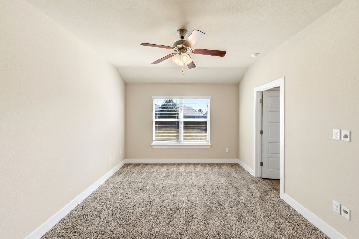 7013 Brick Slope Path Austin, TX 78744 - Photo 14 of 28 Empty room with light colored carpet, lofted ceiling, and ceiling fan