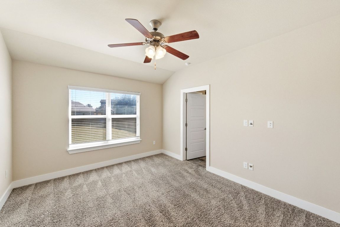 7013 Brick Slope Path Austin, TX 78744 - Photo 15 of 28 Carpeted empty room with lofted ceiling and a ceiling fan