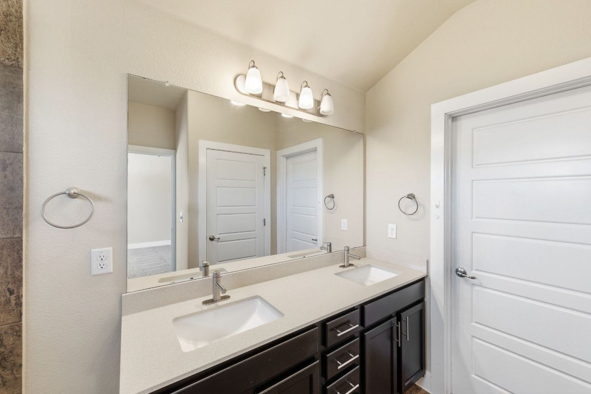 7013 Brick Slope Path Austin, TX 78744 - Photo 16 of 28 Full bath with double vanity and lofted ceiling