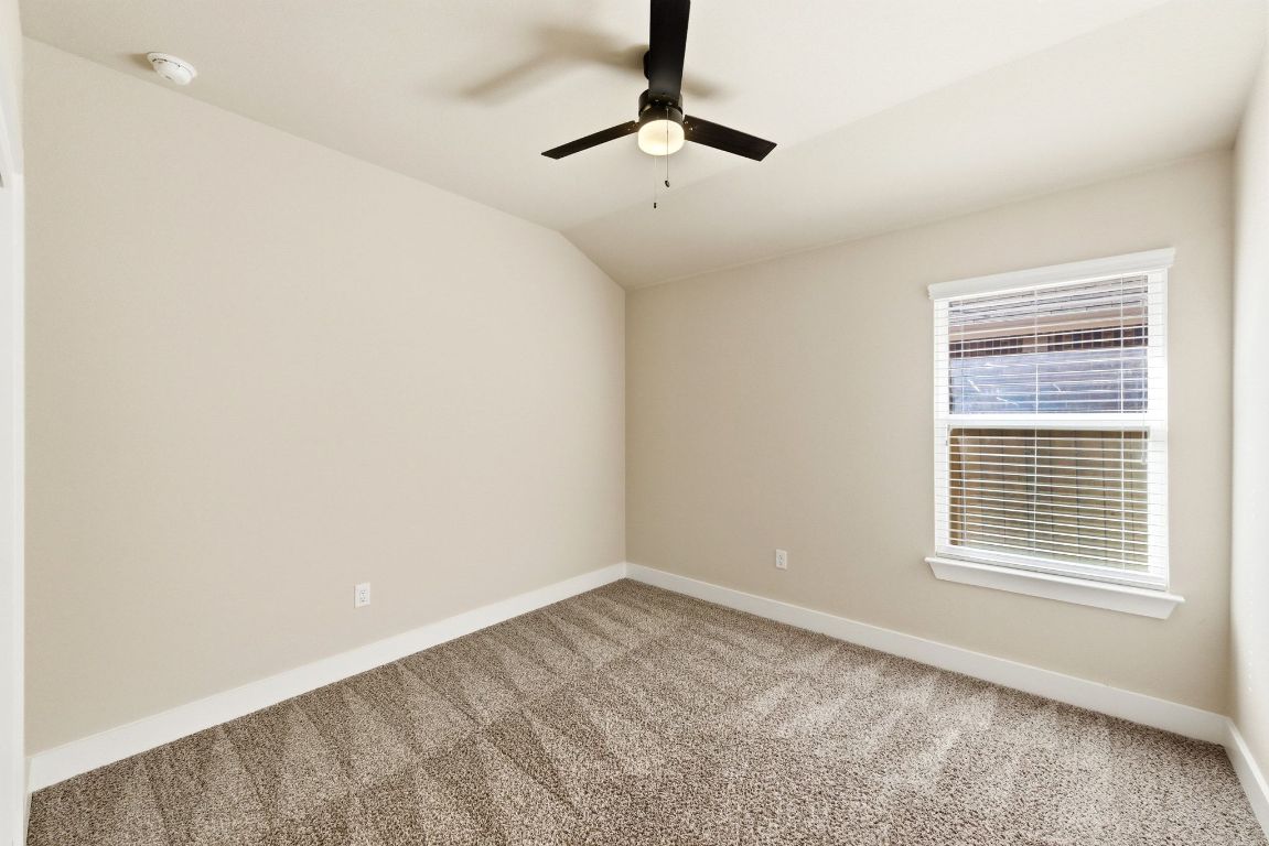 7013 Brick Slope Path Austin, TX 78744 - Photo 19 of 28 Unfurnished room featuring carpet floors, lofted ceiling, ceiling fan, and a smoke detector