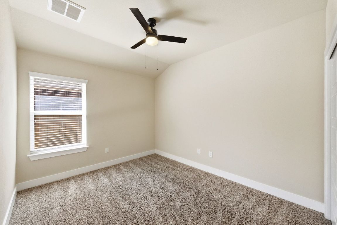 7013 Brick Slope Path Austin, TX 78744 - Photo 20 of 28 Carpeted empty room with lofted ceiling and ceiling fan