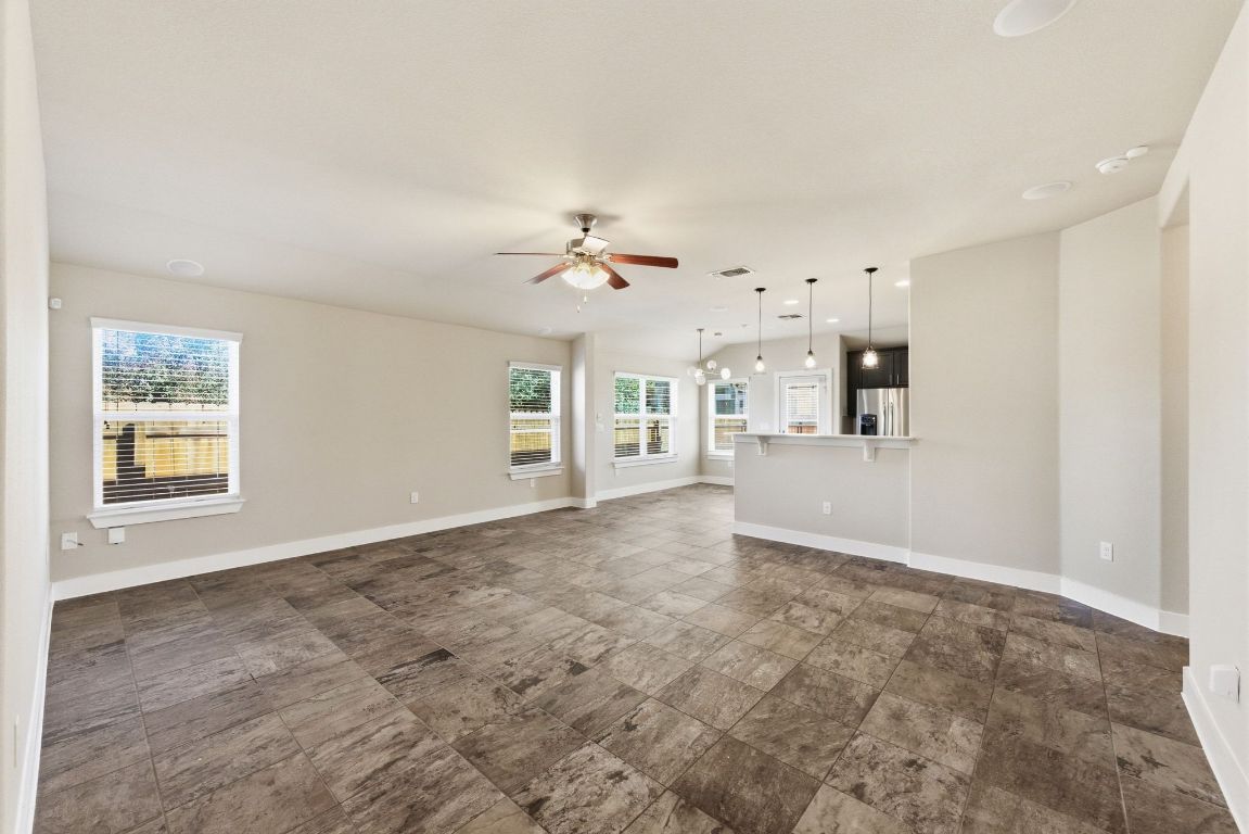 7013 Brick Slope Path Austin, TX 78744 - Photo 5 of 28 Unfurnished living room featuring plenty of natural light and a ceiling fan