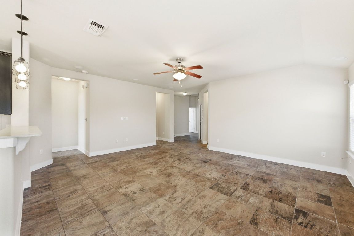 7013 Brick Slope Path Austin, TX 78744 - Photo 7 of 28 Unfurnished living room with ceiling fan and baseboards