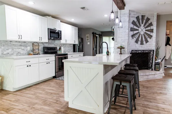 a kitchen with kitchen island granite countertop a stove top oven a sink a counter space and cabinets