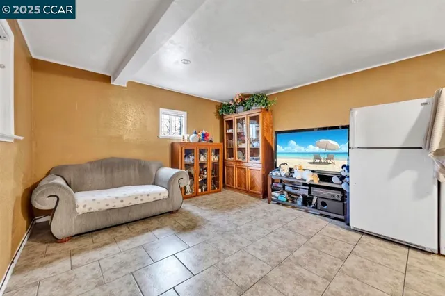 a living room with furniture and a refrigerator