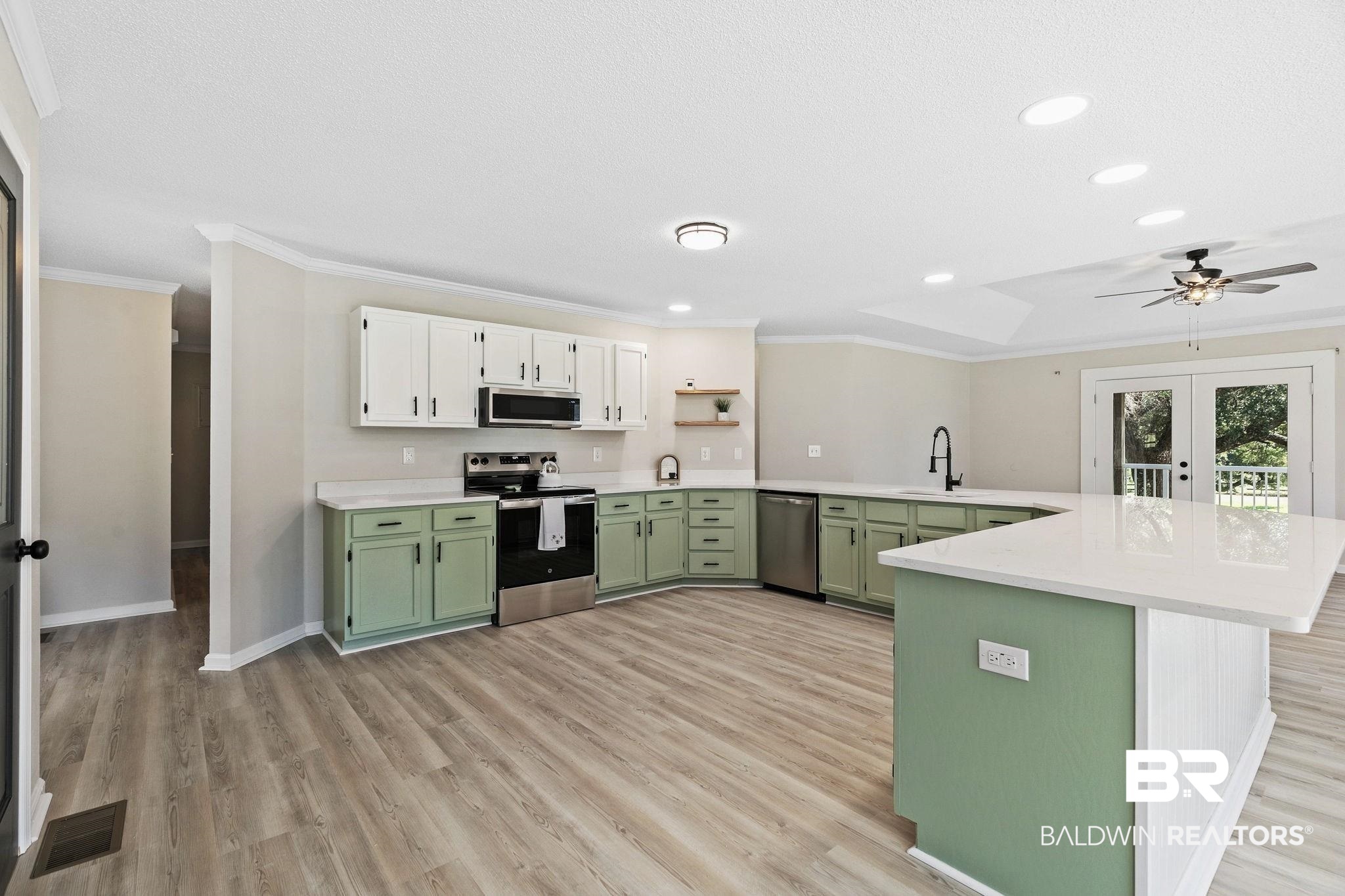 35650 Spring Road North Stapleton, AL 36578 - Photo 20 of 70 Kitchen with green cabinetry, appliances with stainless steel finishes, crown molding, a peninsula, and light wood-type flooring