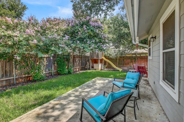 a view of a chair and table in backyard of the house