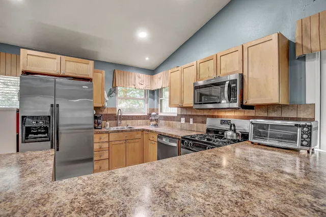 a kitchen with stainless steel appliances granite countertop a refrigerator a stove top oven a sink and dishwasher