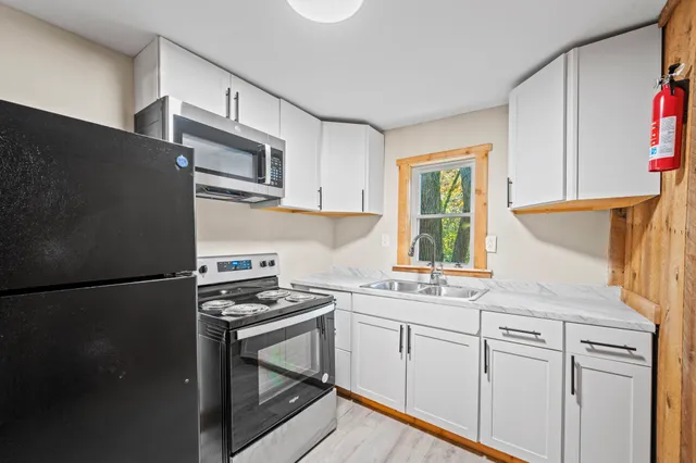 a kitchen with stainless steel appliances granite countertop a refrigerator sink and white cabinets