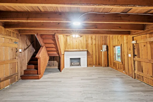 a view of an empty room with wooden floor and stairs