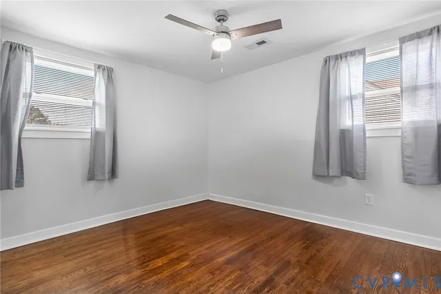 a view of empty room with wooden floor and fan