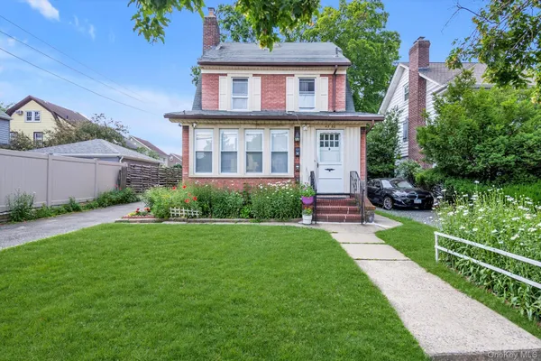 a front view of a house with a yard and potted plants